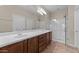 Bathroom featuring double sinks, walk-in shower with glass door, and wood cabinets at 27248 W Mohawk Ln, Buckeye, AZ 85396