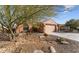 Two-car garage and low-pitched tile roof with drought-tolerant landscaping in the front yard at 27248 W Mohawk Ln, Buckeye, AZ 85396