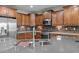 Close-up of kitchen with stainless steel appliances, wood cabinets, backsplash, and stone countertops at 27248 W Mohawk Ln, Buckeye, AZ 85396