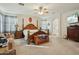 Spacious primary bedroom with a sitting area, four-poster bed, a ceiling fan, and neutral decor at 41011 W Walker Way, Maricopa, AZ 85138