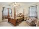 Cozy bedroom with four-poster bed, patterned curtains, and sitting chair at 41011 W Walker Way, Maricopa, AZ 85138