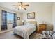 Well-lit bedroom with a ceiling fan, patterned bedding, and a side chair near the window at 41011 W Walker Way, Maricopa, AZ 85138