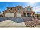 Stunning two-story home featuring a three-car garage and inviting front porch with desert landscaping at 41011 W Walker Way, Maricopa, AZ 85138