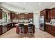 Modern kitchen with dark wood cabinets, stainless steel appliances and a center island with bar stool seating at 41011 W Walker Way, Maricopa, AZ 85138