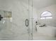 Modern bathroom featuring glass shower with sleek fixtures, marble wall tiles, and soaking tub beneath an arched window at 5246 E Enrose St, Mesa, AZ 85205