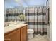 Bathroom with a wood vanity, large mirror and a gray, white, and brown striped shower curtain at 6614 E Portia St, Mesa, AZ 85215