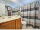 Well-maintained bathroom with a wood vanity, a large mirror, and a patterned shower curtain at 6614 E Portia St, Mesa, AZ 85215