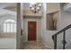Inviting entryway with a stylish chandelier, tiled floor, and wooden front door enhanced by a decorative vase in a niche at 6614 E Portia St, Mesa, AZ 85215