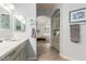 Clean bathroom with light gray cabinets, tile flooring, and an arched doorway leading to the bedroom at 7047 W Saint John Rd, Glendale, AZ 85308