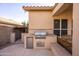 Outdoor built-in kitchen and grill with bar seating and backyard access at 7452 W Los Gatos Dr, Glendale, AZ 85310
