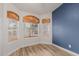 Bright living room features wood-look tile floors, three windows, and a blue accent wall at 7953 W Topeka Dr, Glendale, AZ 85308