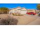 Charming single-story home featuring a well-manicured yard, desert landscaping and a classic red car in the driveway at 10664 E Emerald Ave, Mesa, AZ 85208