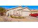 Charming single-story home featuring a well-manicured yard, desert landscaping and a classic red car in the driveway at 10664 E Emerald Ave, Mesa, AZ 85208