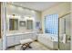 Light-filled bathroom featuring a double vanity, soaking tub with glass block window, and walk-in shower at 11919 E Del Timbre Dr, Scottsdale, AZ 85259