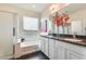 This bathroom features double sinks with granite countertops, white cabinets and an open view to the bathtub at 12246 W Paso Trl, Peoria, AZ 85383