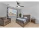 Bedroom with a cozy armchair, a large window, and a modern ceiling fan at 13341 W Yearling Rd, Peoria, AZ 85383