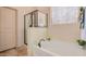 Bright bathroom featuring a soaking tub, glass enclosed shower, and neutral décor at 15788 W Sierra St, Surprise, AZ 85379