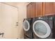 Laundry room featuring dark wood cabinets, a washer and dryer, and back door at 15788 W Sierra St, Surprise, AZ 85379