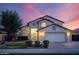 Charming two-story home featuring a two car garage, desert landscaping, and a tile roof at dusk at 16161 W Monte Cristo Ave, Surprise, AZ 85374