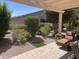 Inviting backyard with covered patio, vibrant flowering shrubs, desert landscaping, and comfortable lounge seating at 20194 N Riverbank Rd, Maricopa, AZ 85138