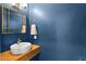 Stylish half-bathroom featuring a modern vessel sink, gold framed mirror, and trendy blue walls at 2020 E Norwood St, Mesa, AZ 85213