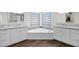 Bright bathroom featuring double sinks, a soaking tub beneath a window, and modern white cabinets with stone countertops at 2020 E Norwood St, Mesa, AZ 85213