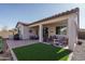 Landscaped backyard with covered patio, artificial grass, and a brick-lined patio at 20392 W Brittlewood Ave, Buckeye, AZ 85396