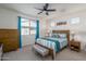 Relaxing bedroom featuring neutral walls, ceiling fan, a large window, and comfortable furnishings at 20392 W Brittlewood Ave, Buckeye, AZ 85396