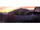 Backyard view of a distant house on a hillside at sunset, framed by landscaping at 2303 E Wescott Dr, Phoenix, AZ 85024