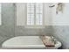 Bright bathroom with a large tub, marble tile and wooden bath tray shelf at 2701 E Hobart St, Gilbert, AZ 85296