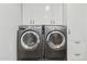 Modern laundry room featuring gray washer and dryer units with overhead cabinets for storage at 2701 E Hobart St, Gilbert, AZ 85296