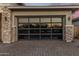 Close-up of a modern garage door with translucent glass panels and stone accents at 30331 N 115Th Ln, Peoria, AZ 85383