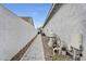 Side yard with brick pathway, utility equipment, and white block wall. Offers functional space while maintaining aesthetic appeal at 3504 E Boot Track Trl, Gilbert, AZ 85296