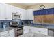 Modern kitchen featuring white cabinets, stainless steel appliances, granite counters, and blue backsplash at 3907 N 143Rd Ln, Goodyear, AZ 85395