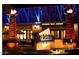 Night view of California Pizza Kitchen with outdoor seating and decorative torches flanking the entrance at 4317 E Williams Dr, Phoenix, AZ 85050