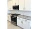 Close-up of kitchen with white cabinets, stainless steel appliances, and tile backsplash at 43527 N Wollemi St, Queen Creek, AZ 85140