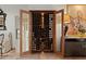 Wooden wine storage cabinet with glass doors revealing racks of wine bottles, adjacent to artwork at 6188 N 29Th Pl, Phoenix, AZ 85016