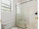 Bathroom featuring a walk-in shower with glass doors, white tile surround, and a toilet with a window at 6350 W Hess St, Phoenix, AZ 85043