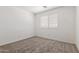 Bedroom with a large window, carpeted floor, and white walls, creating a bright, blank space at 6350 W Hess St, Phoenix, AZ 85043