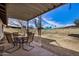 Covered backyard patio with table and chairs overlooks the spacious yard on a bright, sunny day at 6720 W Medlock Dr, Glendale, AZ 85303