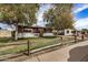 Single-story home with mature trees, a lawn, and charming wood fence, offering curb appeal at 6720 W Medlock Dr, Glendale, AZ 85303