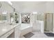 Bright primary bathroom featuring double sinks, soaking tub, and a large window with exterior views at 698 W Merrill Ave, Gilbert, AZ 85233