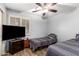 Bedroom featuring twin beds, a ceiling fan, shutters, and a dark-colored dresser with TV at 7322 S Sunset Way, Buckeye, AZ 85326