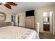 Bedroom featuring a neutral color palette, ceiling fan, dresser with a TV, and an ensuite bathroom at 7322 S Sunset Way, Buckeye, AZ 85326