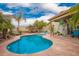 Backyard pool area featuring a freeform pool, palm trees, and cozy seating, perfect for relaxation and entertaining at 7322 S Sunset Way, Buckeye, AZ 85326