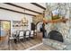 Dining room adjacent to stone fireplace with wood beam ceiling and wood-look tile flooring at 7650 E Culver St, Mesa, AZ 85207