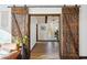 Rustic barn doors open to an entry hall showcasing hardwood floors and an open-concept living space at 7650 E Culver St, Mesa, AZ 85207