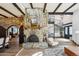 Open concept living room with a stone fireplace, wood beam ceiling, spiral staircase, and wood-look tile flooring at 7650 E Culver St, Mesa, AZ 85207