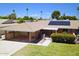 Single-story home with carport, solar panels, and beautiful desert landscaping, including flowering bushes, and mature trees at 10816 W Venturi Dr, Sun City, AZ 85351