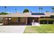 Single story home featuring a covered carport, solar panels, and a well-maintained front lawn with flowering bushes at 10816 W Venturi Dr, Sun City, AZ 85351
